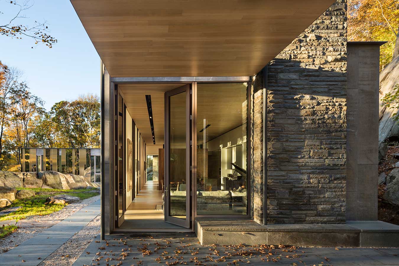 <p>At the end of the living/dining space, a canopy continues the space out over a stone patio that extends the interior out into the landscape along the steep ridge line as it rides out beyond the house to the southeast. <br><small>&copy; Peter Aaron</small></p>