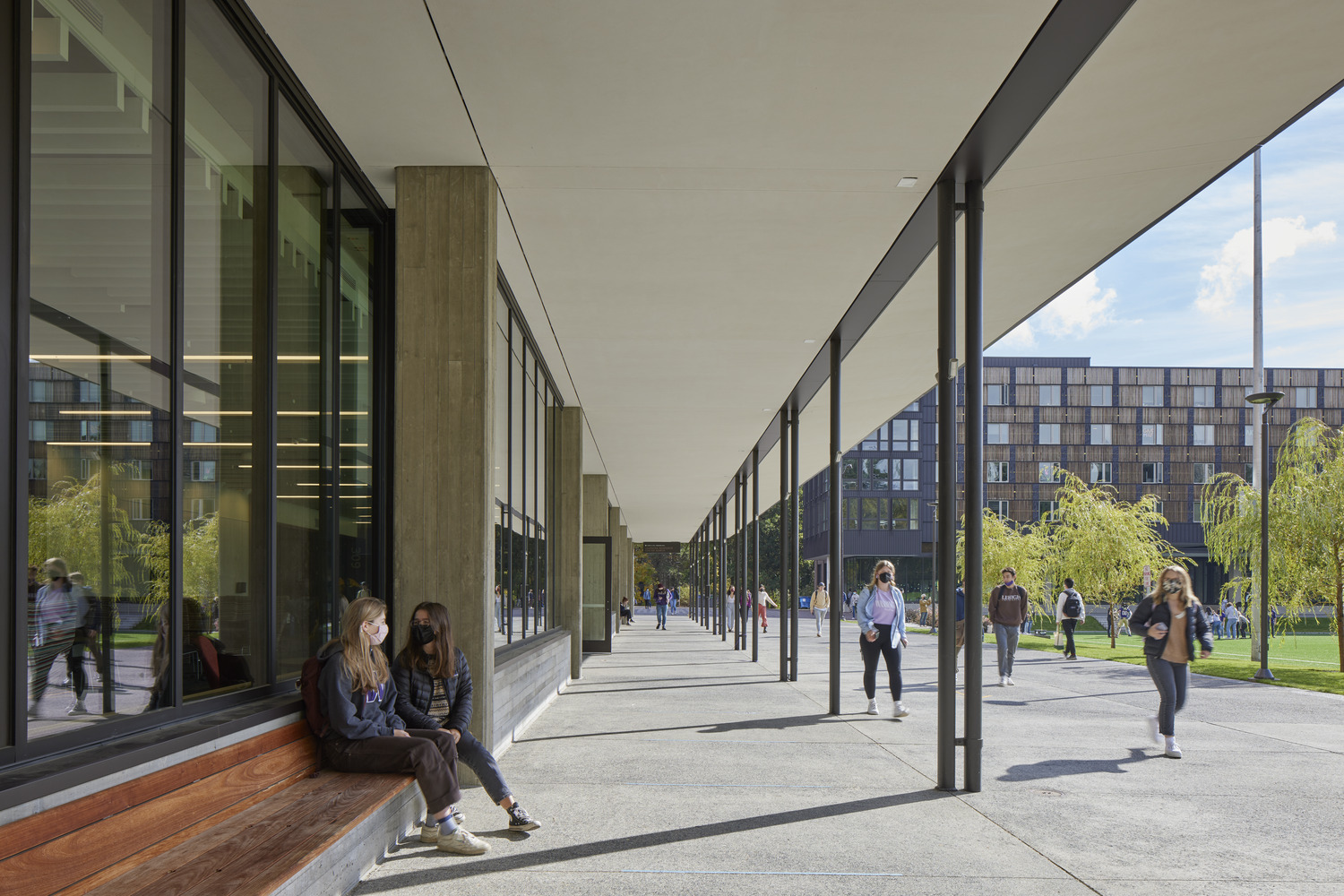 <p>Outside the Learning Resource Center on Madrona Hall's ground level, students take advantage of built-in benches and a deep canopy for outdoor socializing. With a depth of 17-feet, the canopy provides shade for the full height glass windows, shielding from solar heat gain | <small>&copy; Bruce Damonte</small></p>